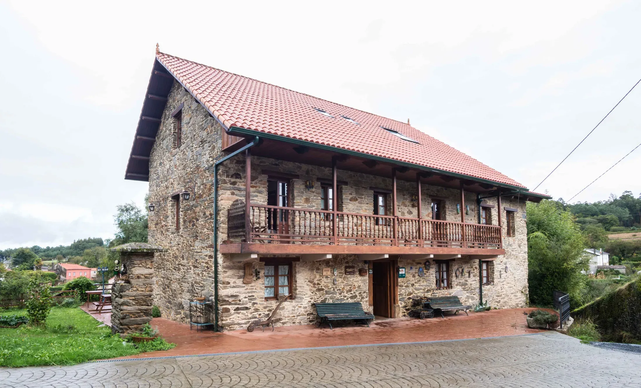 Stone façade of Casa de Sixto with a red tile roof and a wooden gallery