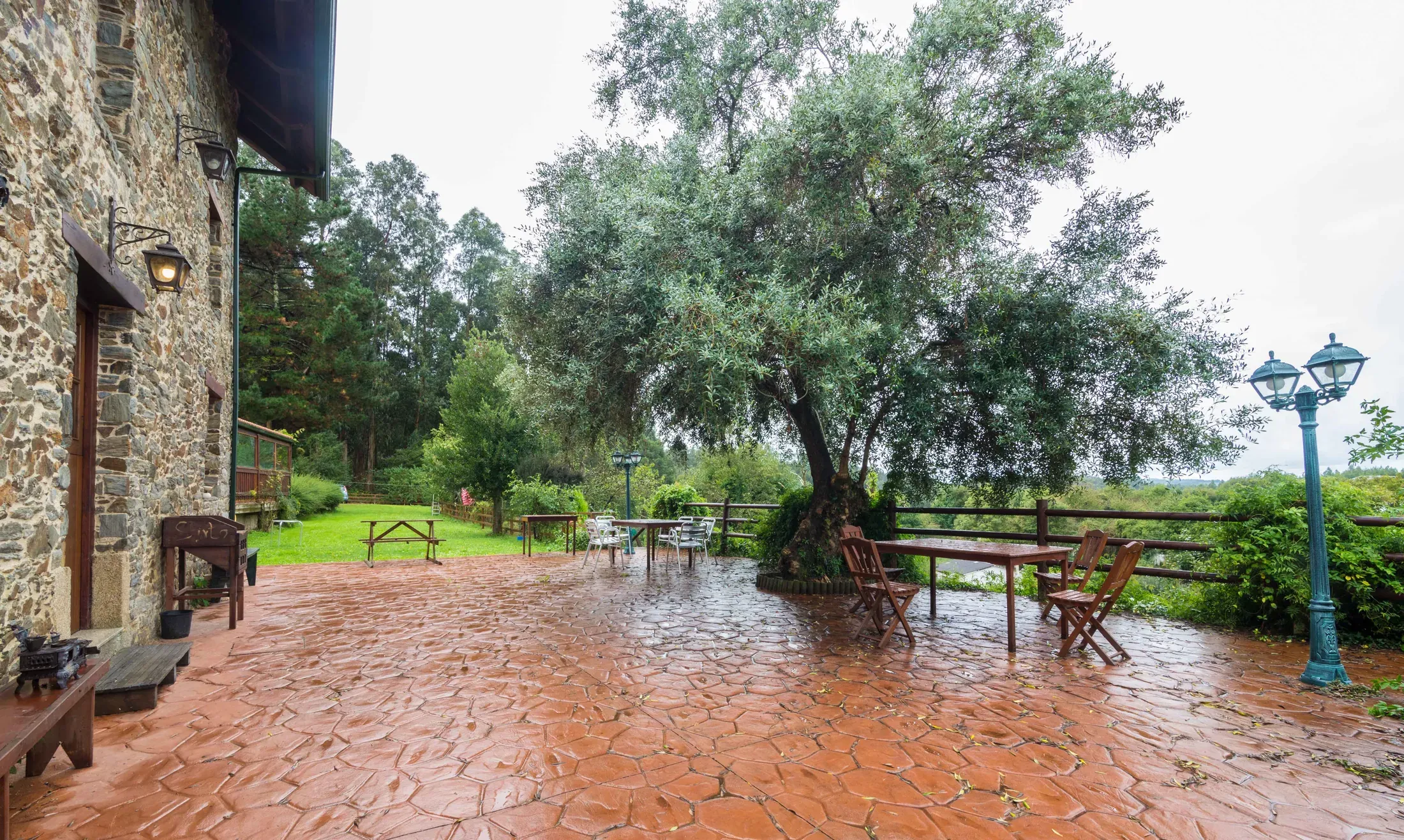 Outdoor terrace with brick paving, a wooden table and the garden