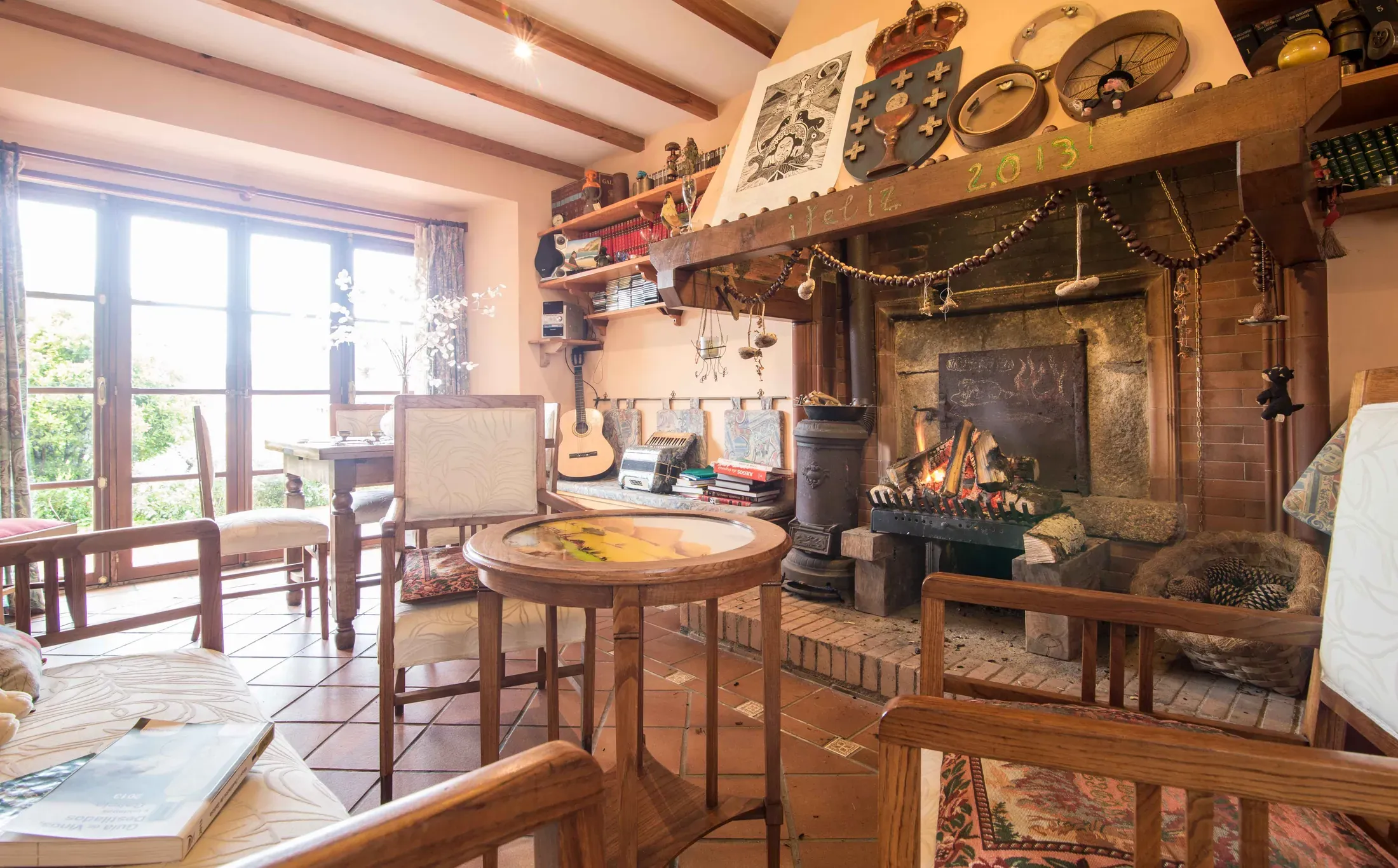 Living room with a lit fireplace, a large window and guitars on the wall