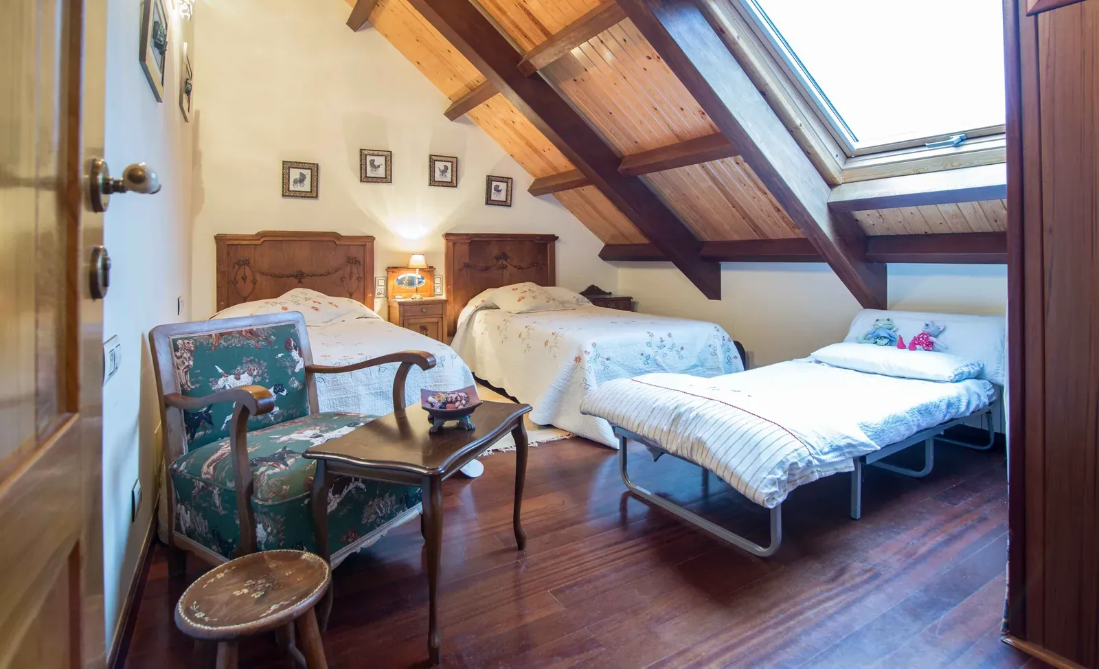 Habitación con techo de madera y claraboya, sillón y mesita