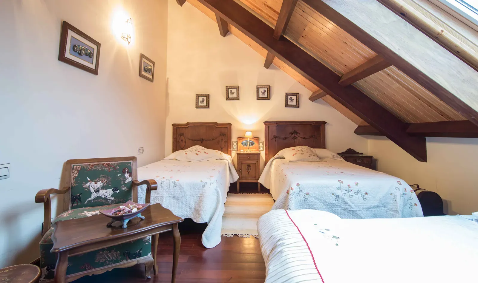 Habitación con dos camas, sillones y techo de vigas de madera