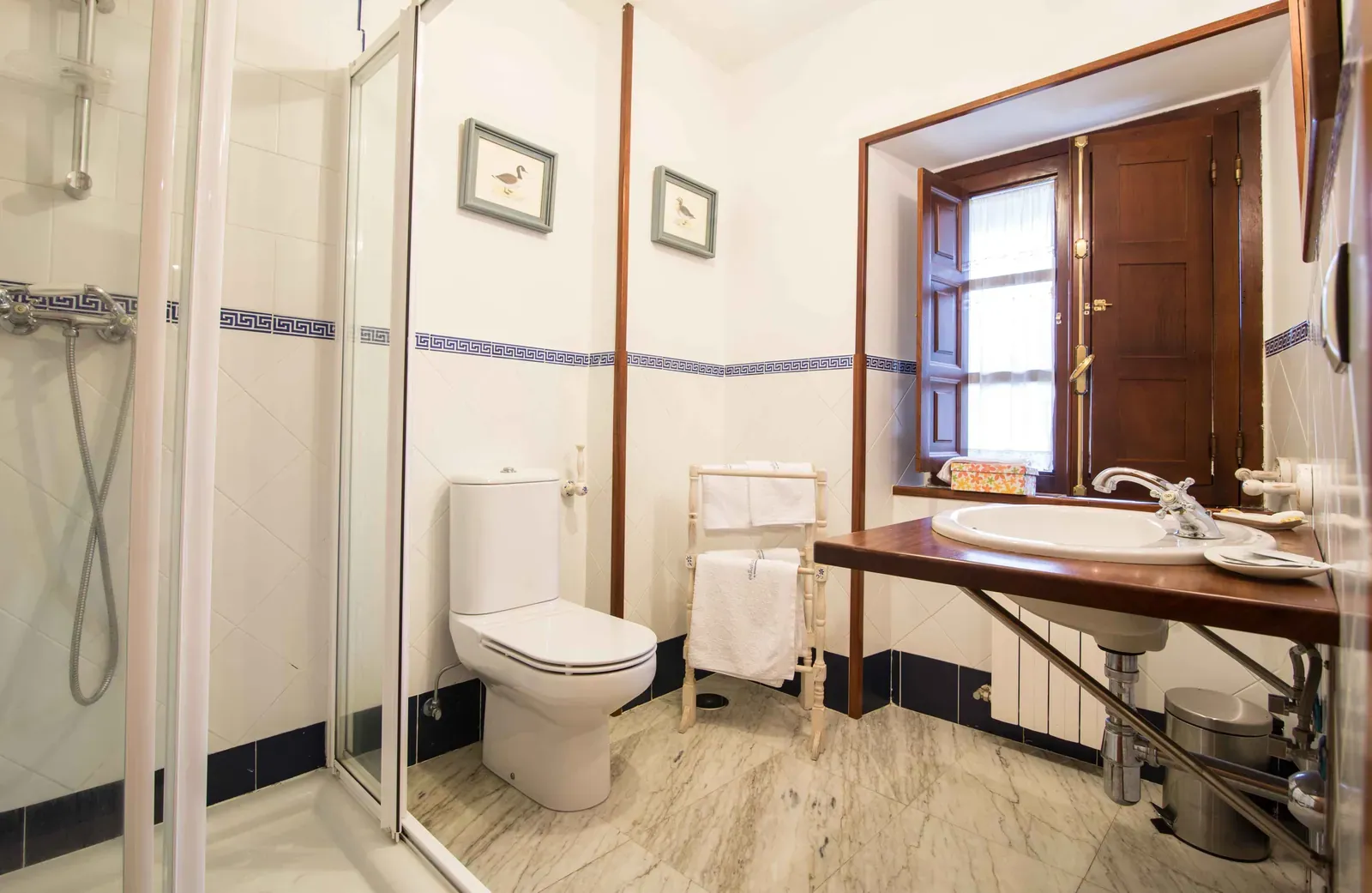 Baño con ducha abierta, inodoro y espejo con marco de madera